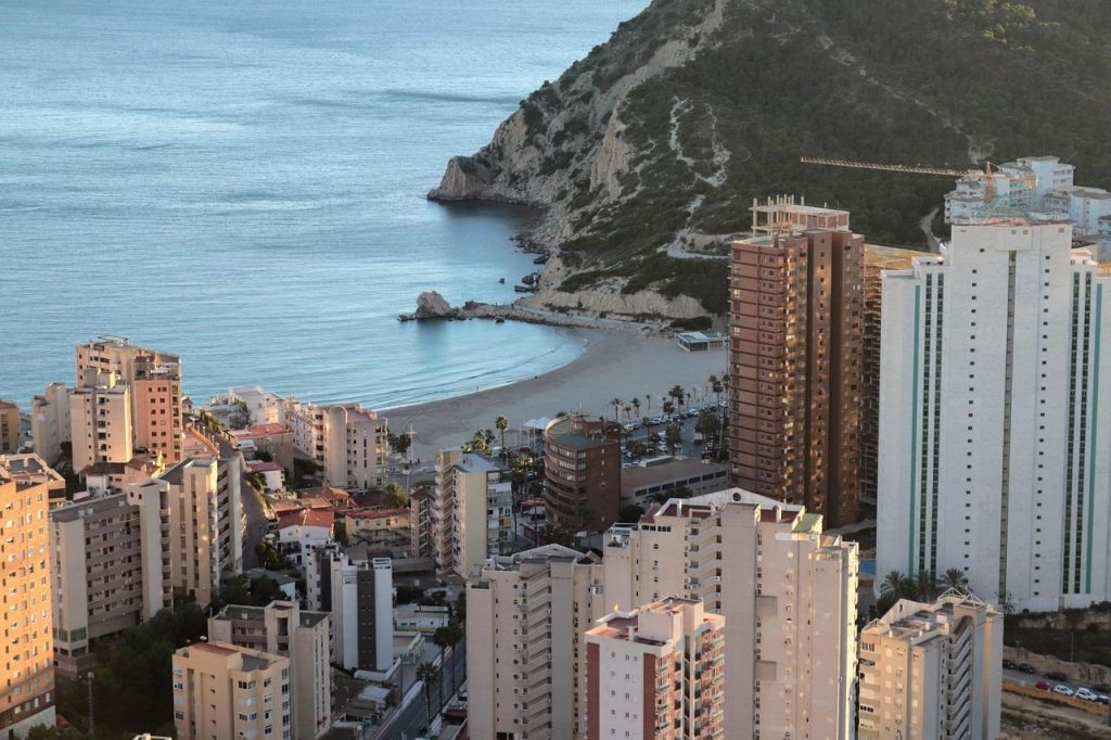 Professionaal die werkt tijdens een workation in Spanje met uitzicht op zee, combinatie van productiviteit en ontspanning